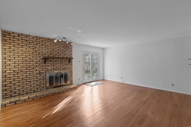 unfurnished living room with hardwood / wood-style flooring and a brick fireplace