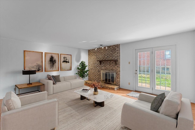 living room featuring ceiling fan, light hardwood / wood-style flooring, and a brick fireplace