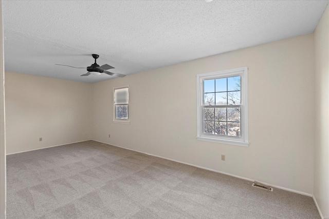 carpeted spare room with a textured ceiling and ceiling fan