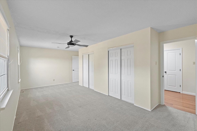 unfurnished bedroom with a textured ceiling, ceiling fan, and light carpet