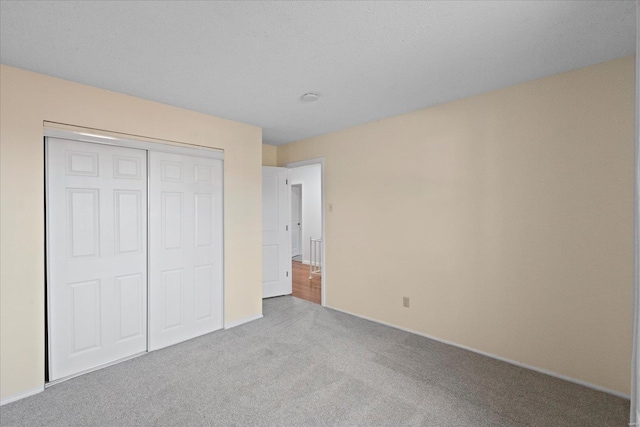 unfurnished bedroom with light colored carpet and a closet