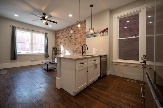 kitchen with light stone countertops, sink, decorative light fixtures, dark hardwood / wood-style floors, and white cabinetry