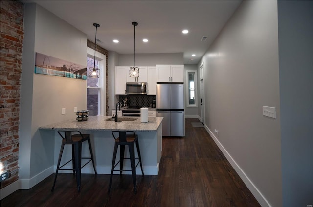 kitchen featuring pendant lighting, sink, white cabinetry, kitchen peninsula, and stainless steel appliances