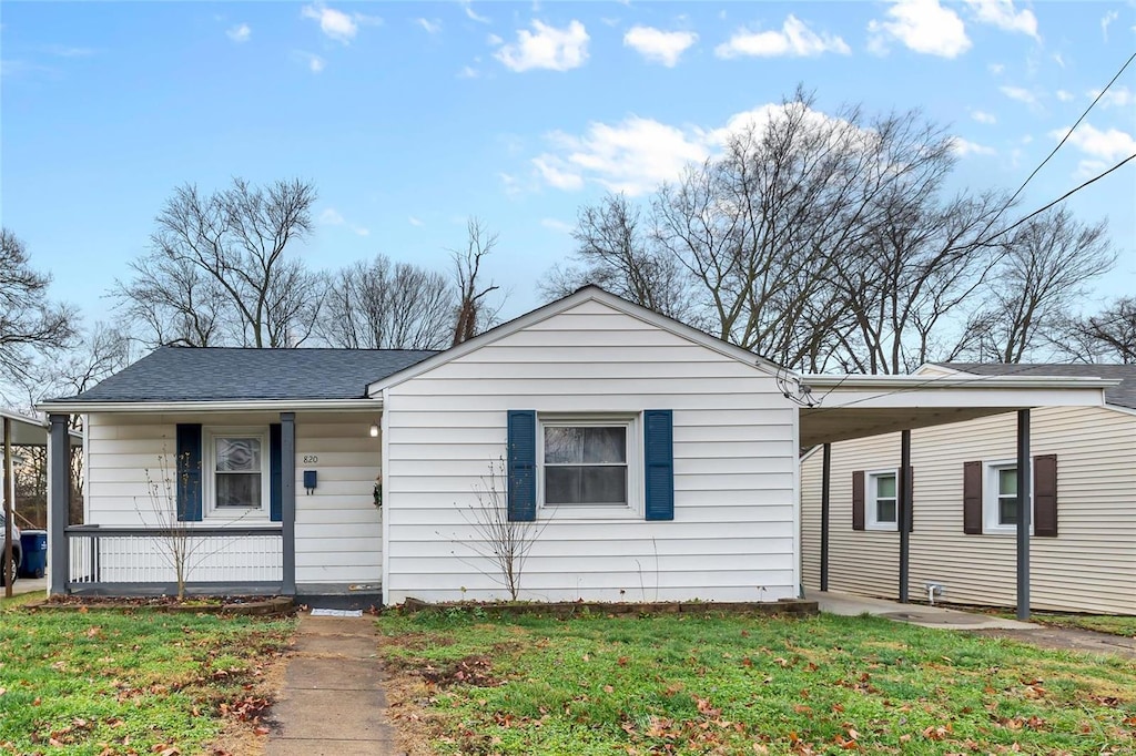 view of front facade with a carport, a porch, and a front yard