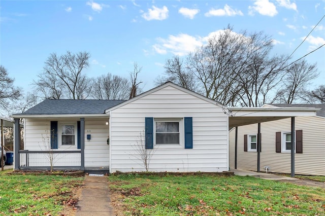 view of front facade with a carport, a porch, and a front yard