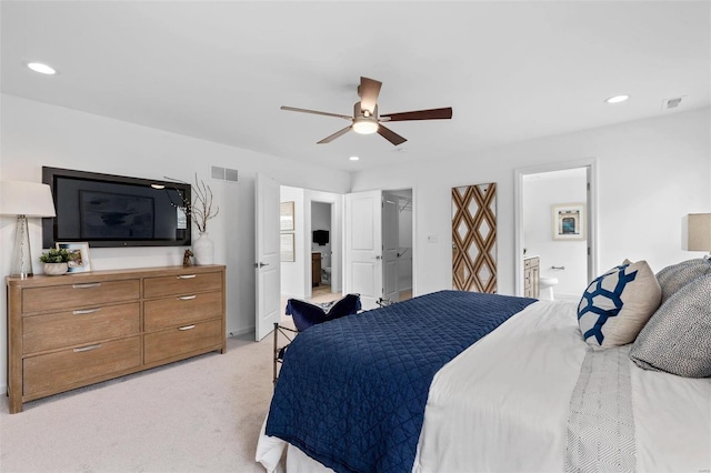 bedroom with ceiling fan, a spacious closet, ensuite bathroom, light colored carpet, and a closet