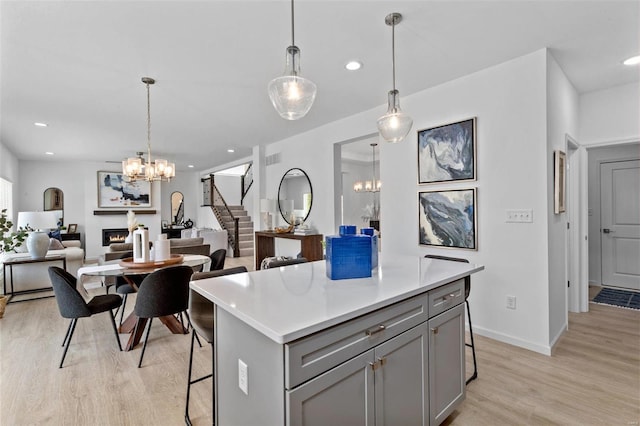 kitchen featuring a breakfast bar area, gray cabinets, light hardwood / wood-style flooring, and hanging light fixtures