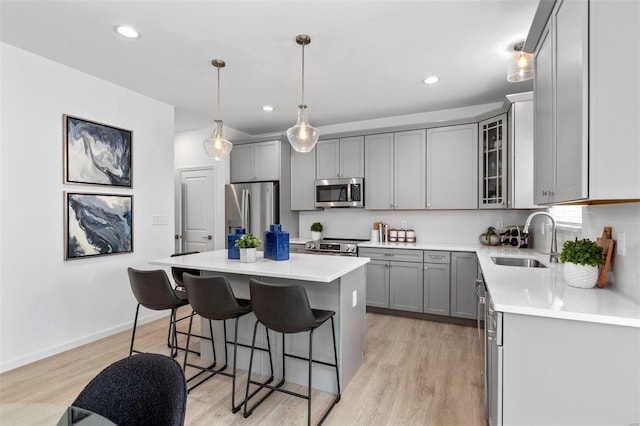 kitchen featuring sink, a center island, stainless steel appliances, light hardwood / wood-style flooring, and pendant lighting