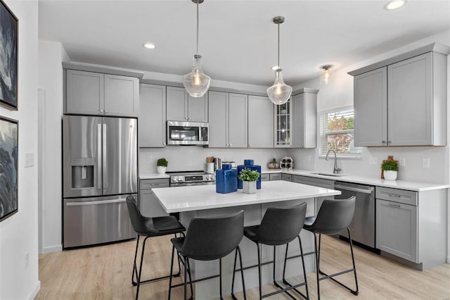 kitchen with pendant lighting, gray cabinetry, sink, appliances with stainless steel finishes, and a kitchen island