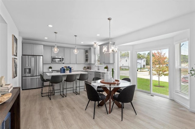 dining space featuring a chandelier, sink, a healthy amount of sunlight, and light wood-type flooring