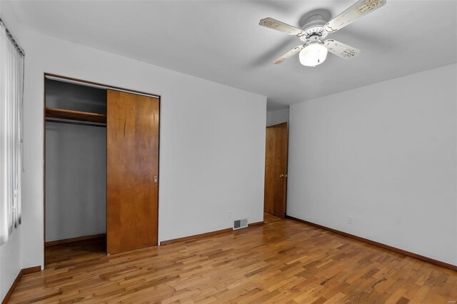 unfurnished bedroom featuring a closet, light hardwood / wood-style floors, and ceiling fan