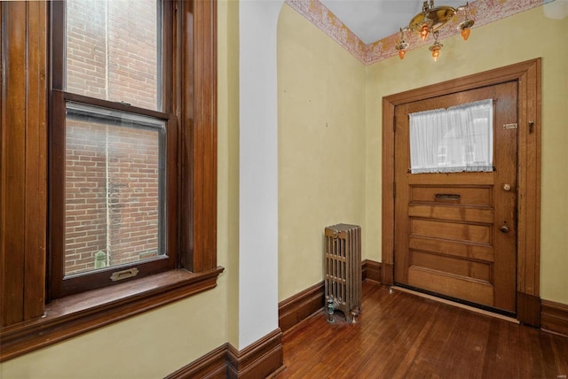 entryway featuring radiator, wood finished floors, baseboards, and arched walkways