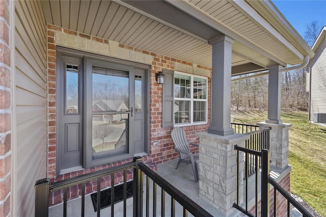 doorway to property with covered porch and brick siding