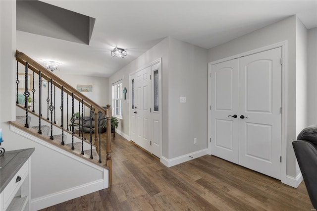 foyer entrance with stairs, dark wood-style floors, and baseboards