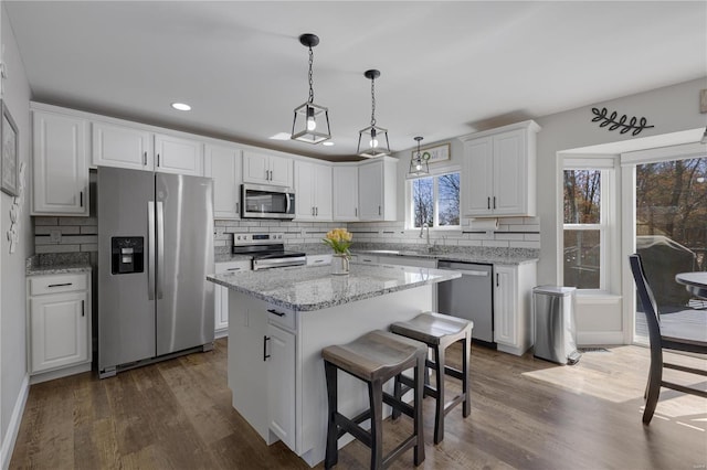 kitchen featuring stainless steel appliances, dark wood-style flooring, white cabinetry, and a kitchen island