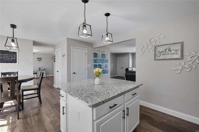 kitchen featuring dark wood-type flooring, a center island, white cabinetry, and baseboards