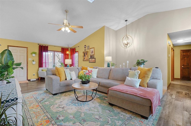 living room with wood-type flooring, ceiling fan with notable chandelier, and vaulted ceiling