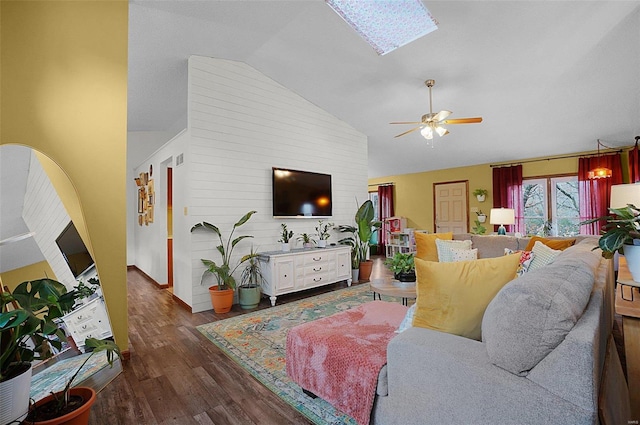 living room featuring a skylight, high vaulted ceiling, dark hardwood / wood-style floors, and ceiling fan