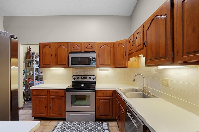 kitchen featuring backsplash, sink, light tile patterned flooring, and appliances with stainless steel finishes