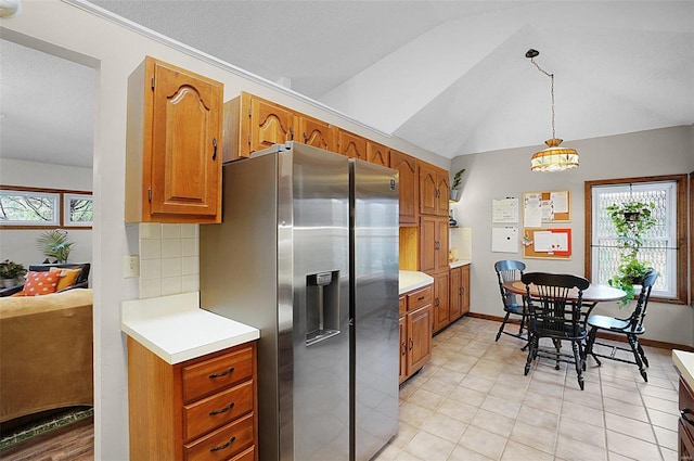 kitchen with decorative backsplash, a textured ceiling, vaulted ceiling, decorative light fixtures, and stainless steel fridge with ice dispenser