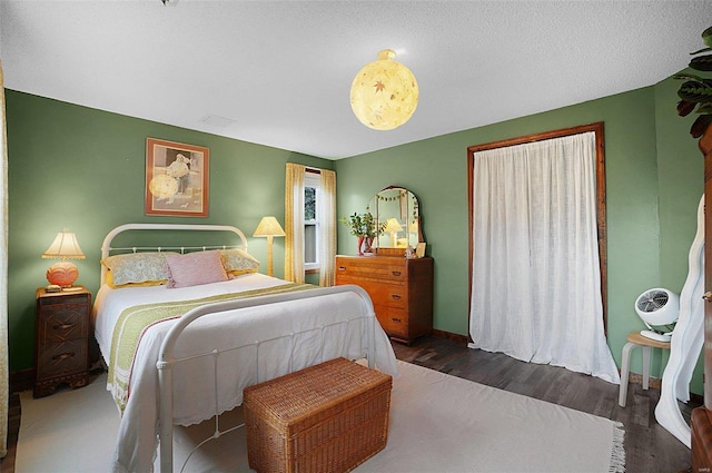 bedroom with a textured ceiling and dark hardwood / wood-style floors