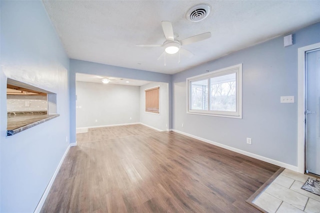 unfurnished living room with ceiling fan, light hardwood / wood-style flooring, and a textured ceiling