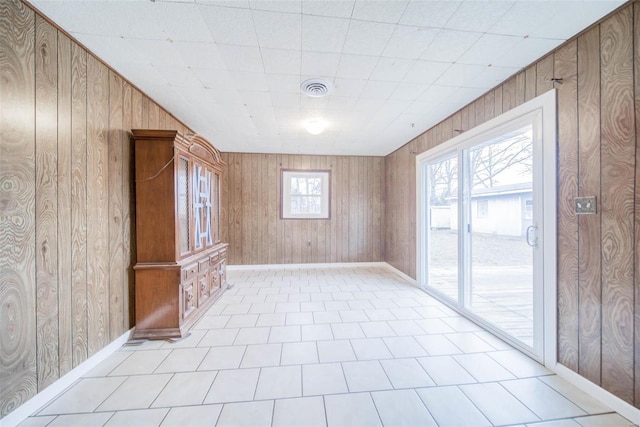 unfurnished room with wood walls and a healthy amount of sunlight