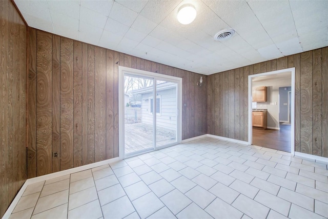 spare room with wooden walls and light tile patterned floors