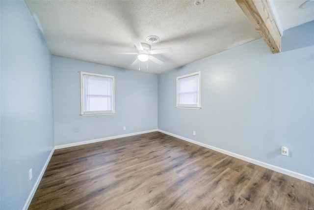 spare room featuring beamed ceiling, ceiling fan, wood-type flooring, and a textured ceiling