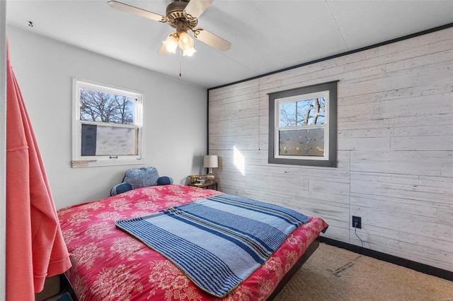 bedroom with ceiling fan, wood walls, and carpet floors