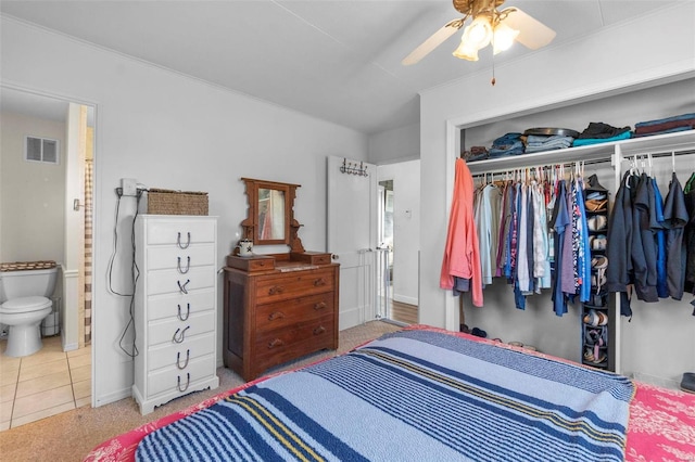 tiled bedroom featuring connected bathroom, a closet, crown molding, and ceiling fan