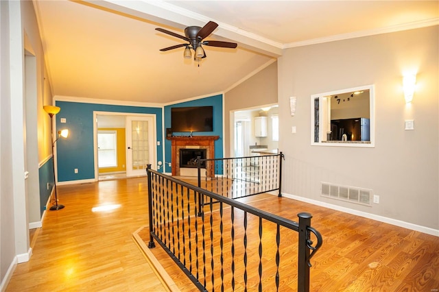 corridor featuring hardwood / wood-style flooring, ornamental molding, and vaulted ceiling