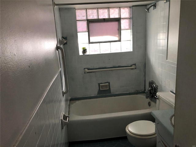 full bathroom featuring vanity, tiled shower / bath combo, tile walls, tile patterned flooring, and toilet