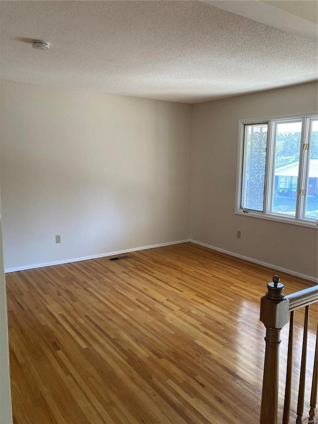 empty room with hardwood / wood-style floors and a textured ceiling