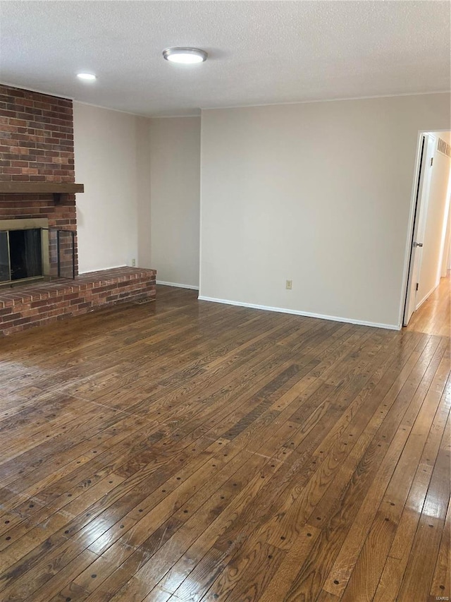 unfurnished living room with a fireplace, dark hardwood / wood-style flooring, and a textured ceiling