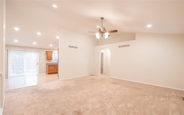 unfurnished living room with ceiling fan, high vaulted ceiling, and light carpet