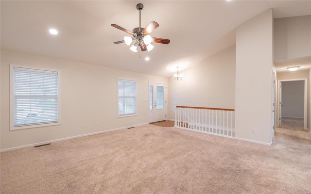 spare room featuring light carpet, ceiling fan with notable chandelier, and vaulted ceiling