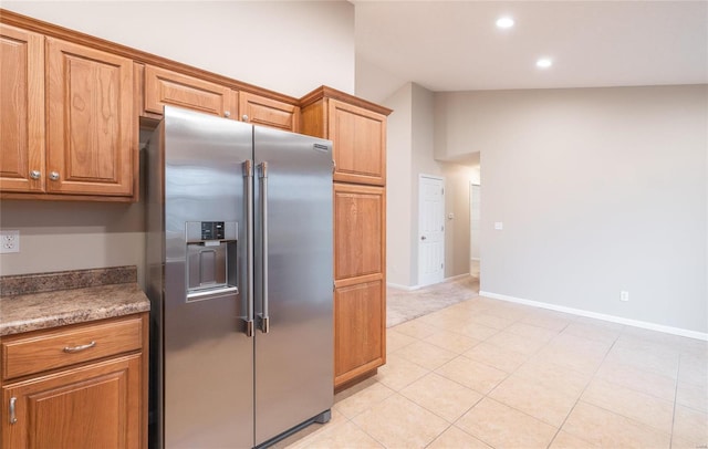 kitchen featuring light tile patterned floors, dark stone counters, and high end refrigerator