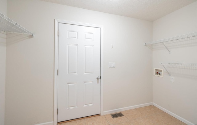 washroom featuring washer hookup, light tile patterned floors, and a textured ceiling