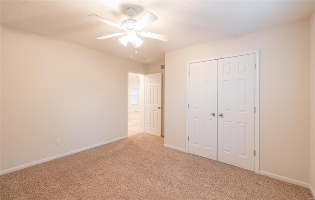 unfurnished bedroom with ceiling fan, light carpet, and a closet