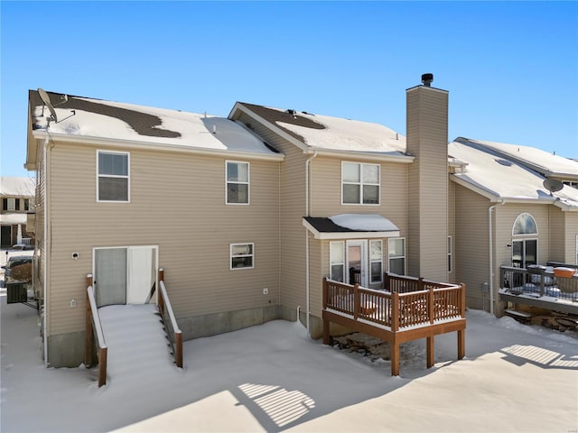 snow covered back of property featuring a wooden deck