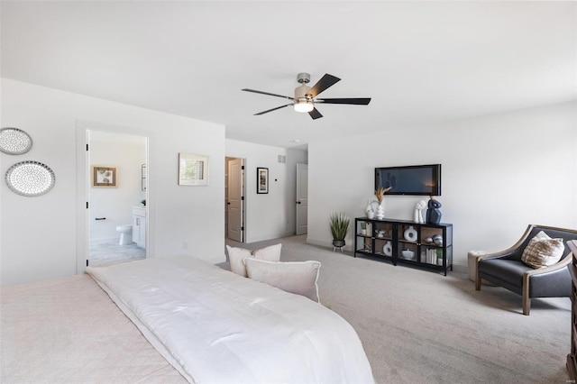 bedroom with ceiling fan, ensuite bathroom, and light carpet