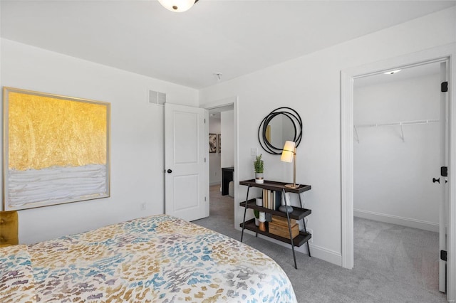 carpeted bedroom with a walk in closet and a closet