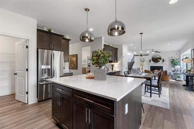 kitchen featuring dark brown cabinetry, a center island, stainless steel fridge, pendant lighting, and light wood-type flooring