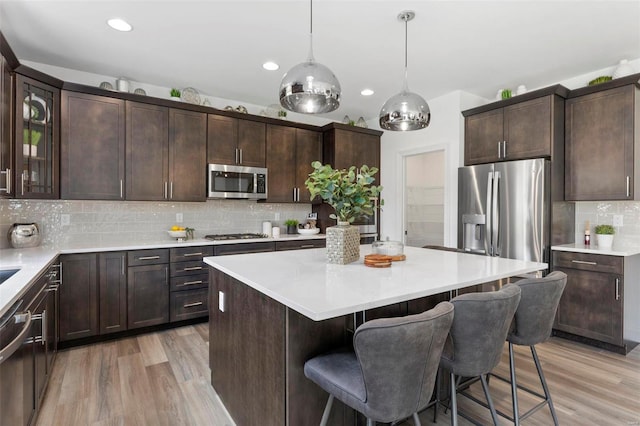 kitchen featuring tasteful backsplash, dark brown cabinetry, stainless steel appliances, and light hardwood / wood-style floors