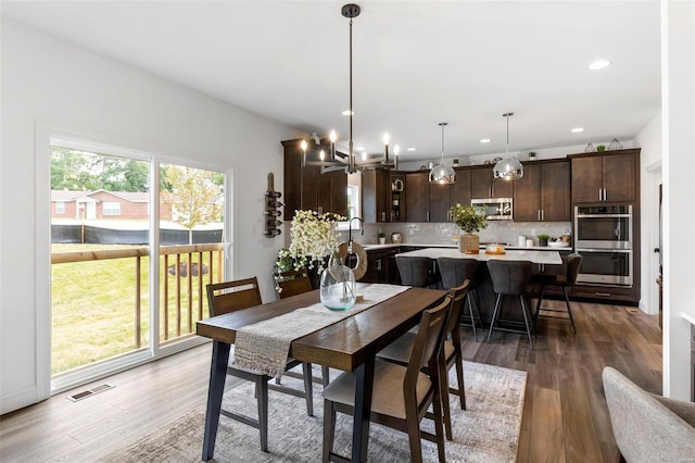 dining area with dark wood-type flooring, a wealth of natural light, and a chandelier