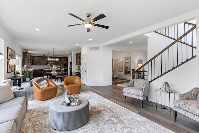 living room with ceiling fan with notable chandelier and dark wood-type flooring