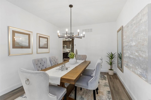 dining space with dark wood-type flooring and a notable chandelier