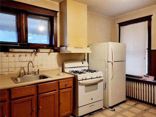 kitchen featuring backsplash, radiator heating unit, white appliances, and sink