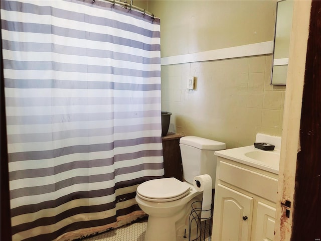 bathroom with tile patterned flooring, vanity, toilet, and tile walls